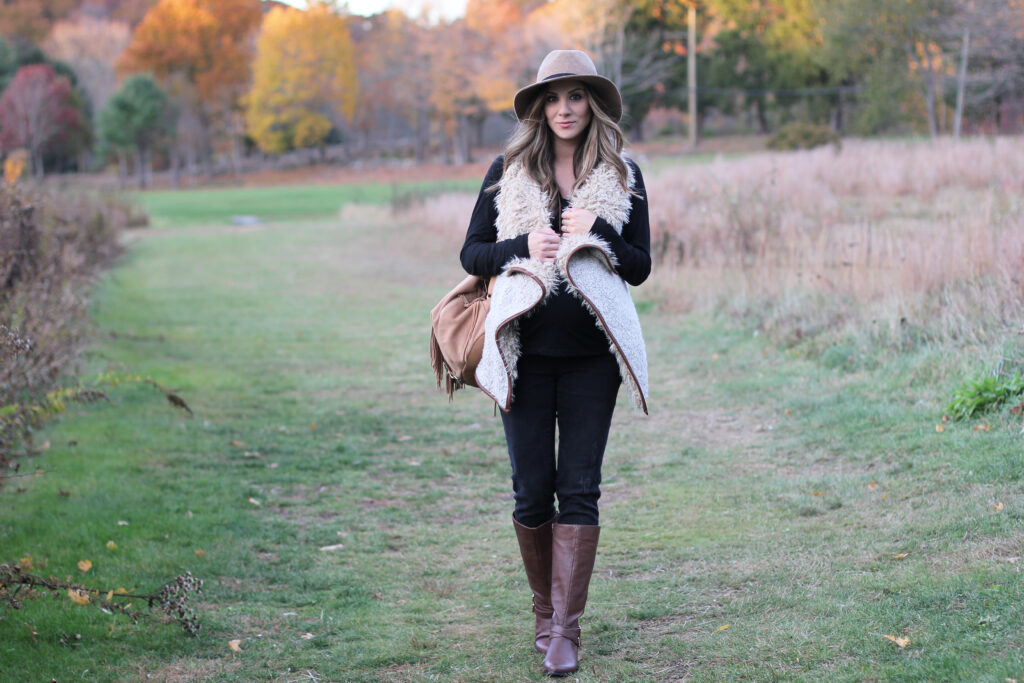 Fall maternity fashion in this fur and leather vest with a wool hat and riding boots.