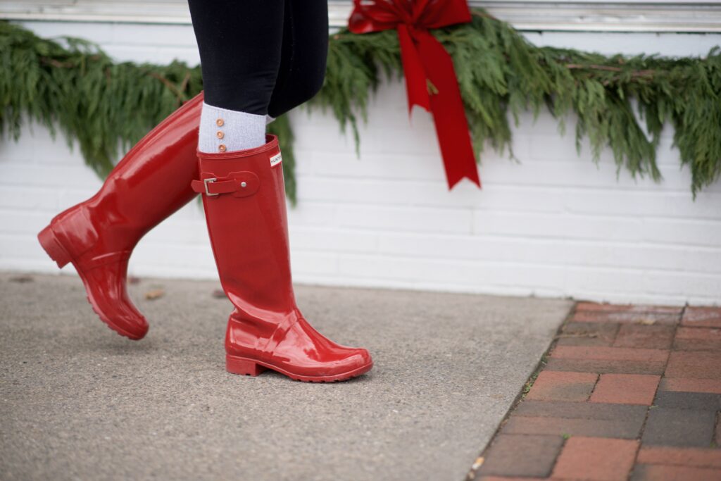 Cozy casual mom outfit with red Hunter boots, leggings, an oversized sweater, and puffy vest.