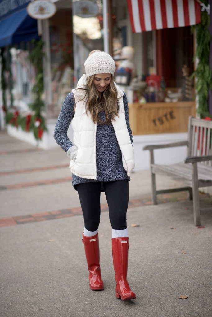 Cozy casual mom outfit with red Hunter boots, leggings, an oversized sweater, and puffy vest.