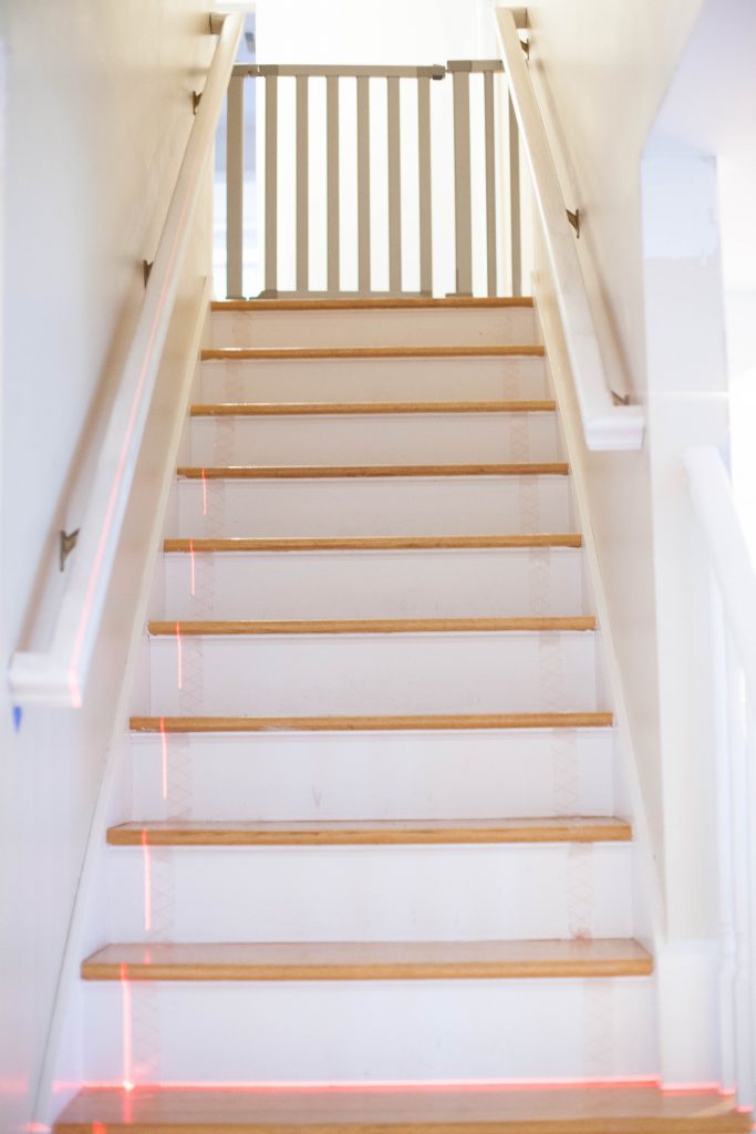 A simple guide to making a DIY stair runner using area rugs and carpet tape for a low cost solution for loud stairs!