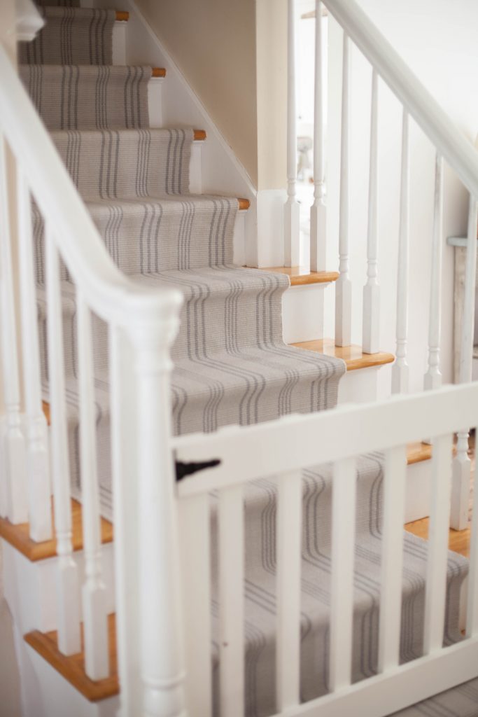 A simple guide to making a DIY stair runner using area rugs and carpet tape for a low cost solution for loud stairs!