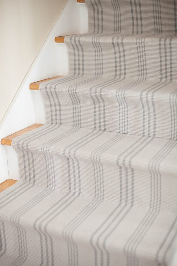 A simple guide to making a DIY stair runner using area rugs and carpet tape for a low cost solution for loud stairs!