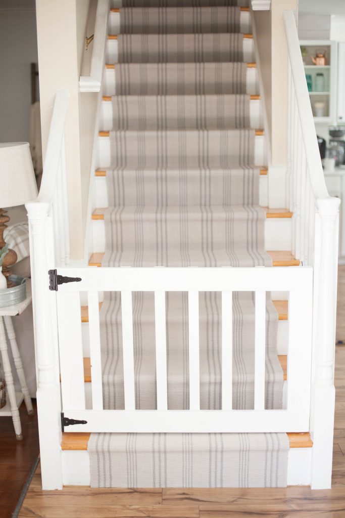 A simple guide to making a DIY stair runner using area rugs and carpet tape for a low cost solution for loud stairs!