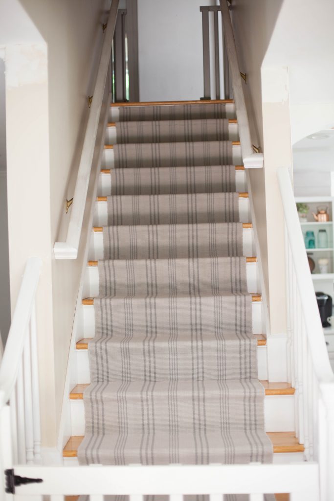 A simple guide to making a DIY stair runner using area rugs and carpet tape for a low cost solution for loud stairs!