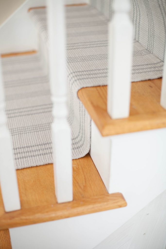 A simple guide to making a DIY stair runner using area rugs and carpet tape for a low cost solution for loud stairs!