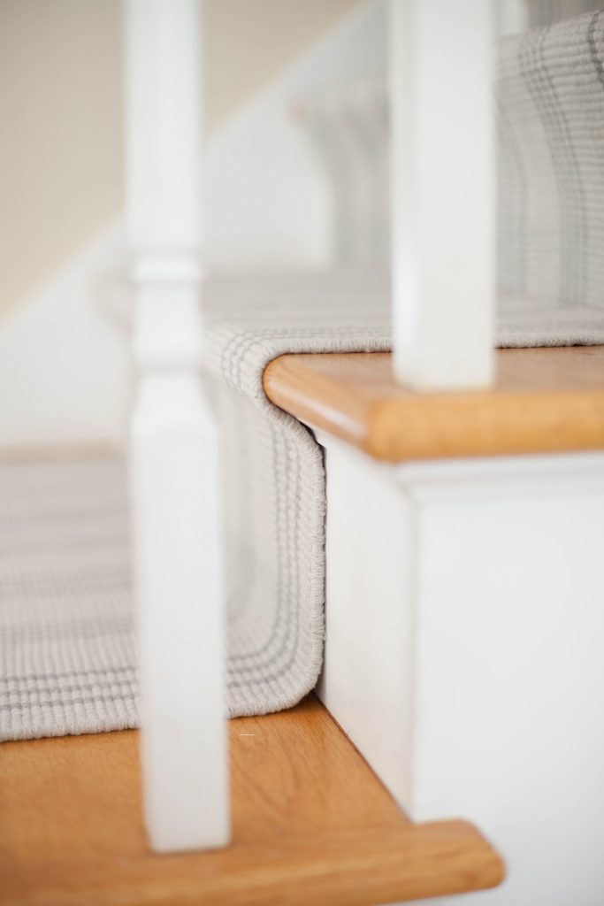 A simple guide to making a DIY stair runner using area rugs and carpet tape for a low cost solution for loud stairs!