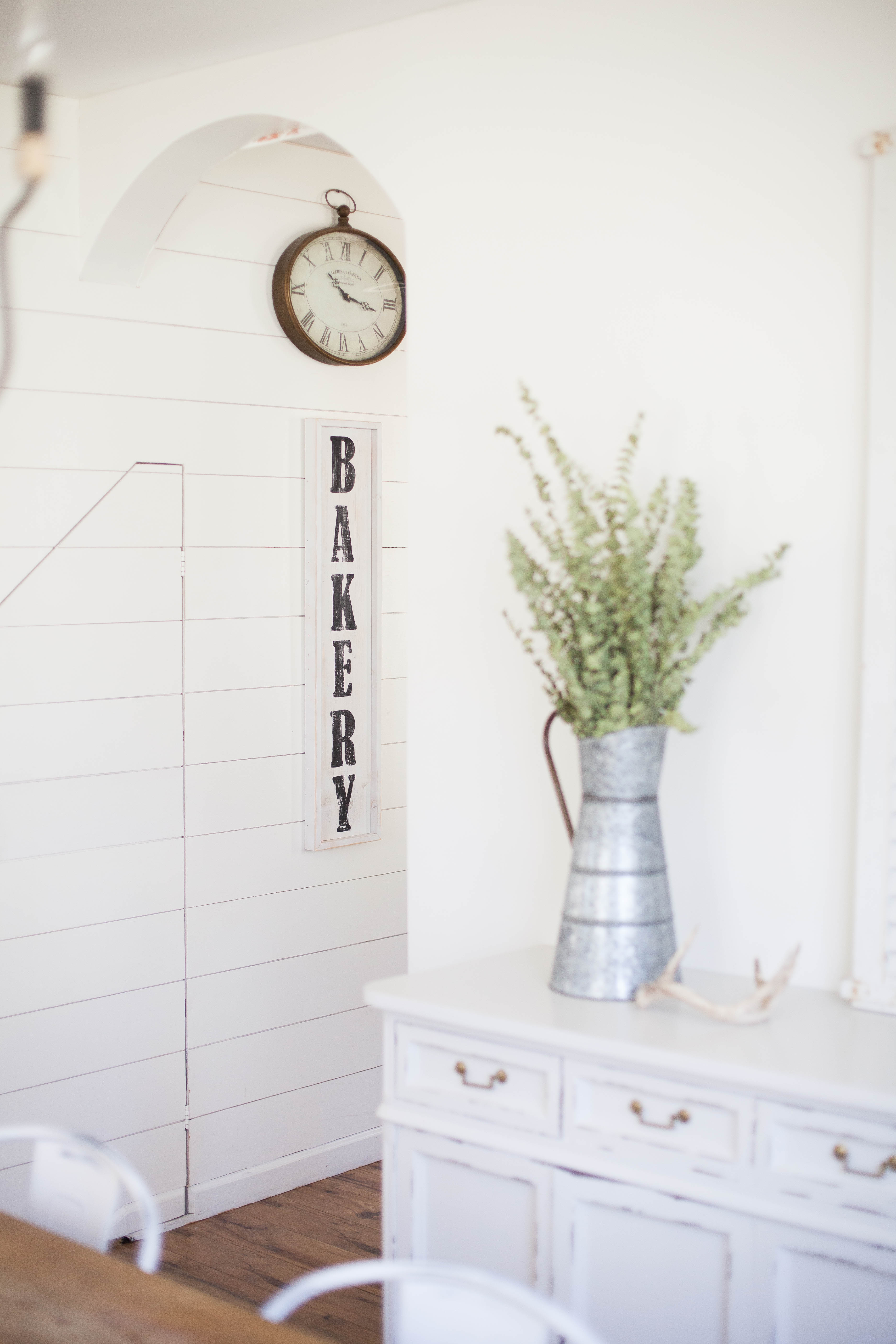 This spring cottage dining room is complete with shiplap walls, antique furniture, and a handmade farmhouse table