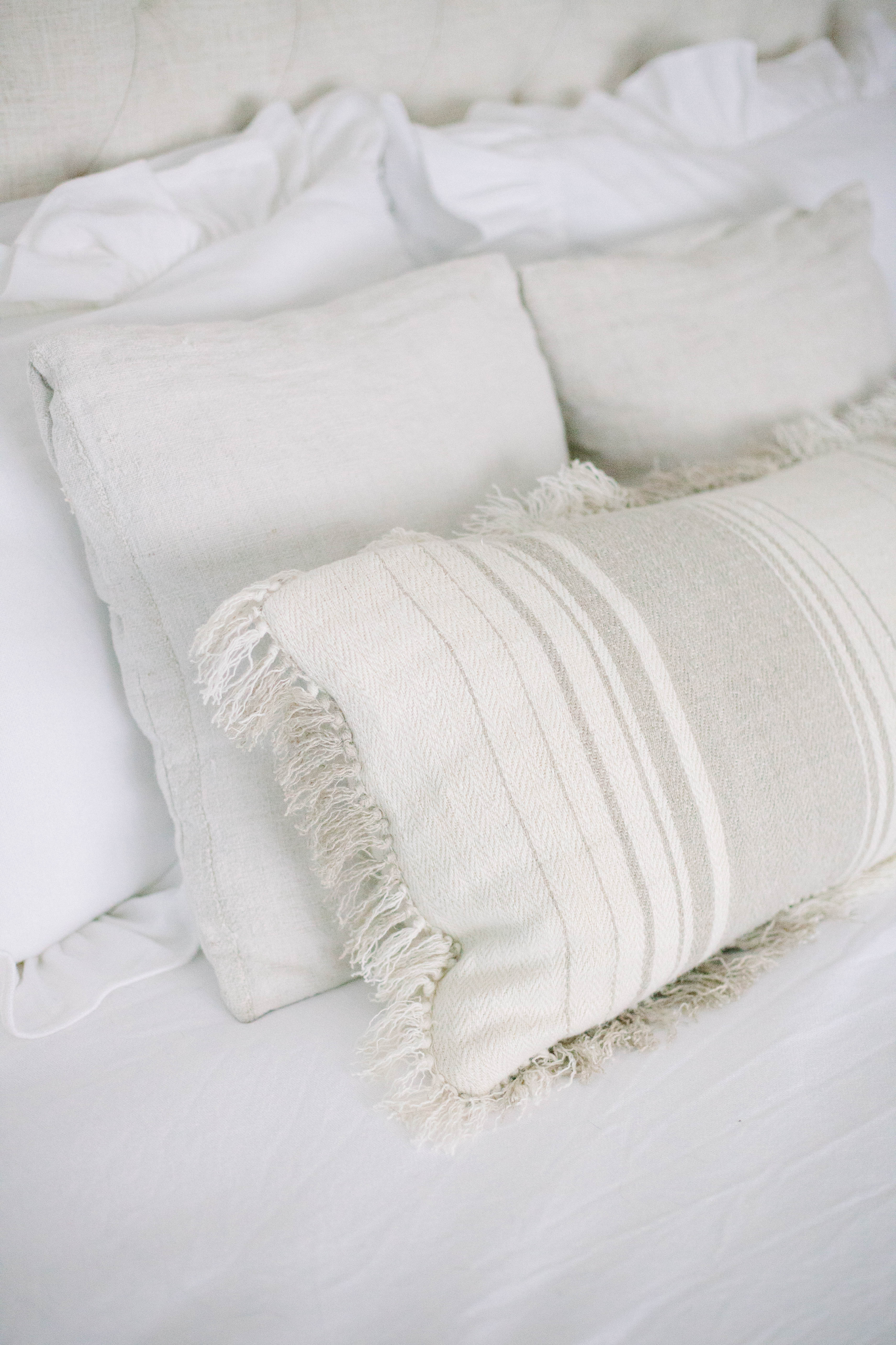 The summer cottage master bedroom is romantic with it's upholstered headboard and waterfall bedding, complete with a jute rug.